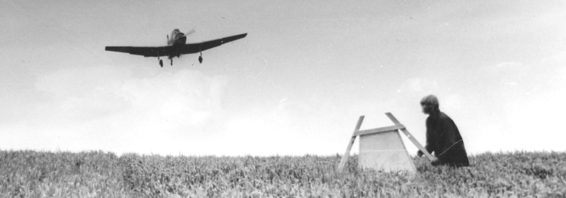 Ein einmotoriges Flugzeug dicht über einem Feld.